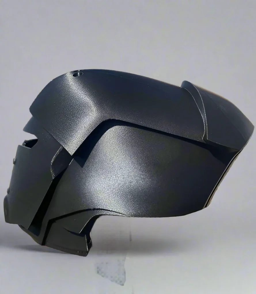 Black printed helmet shell resting on a pale surface, viewed from the side.
