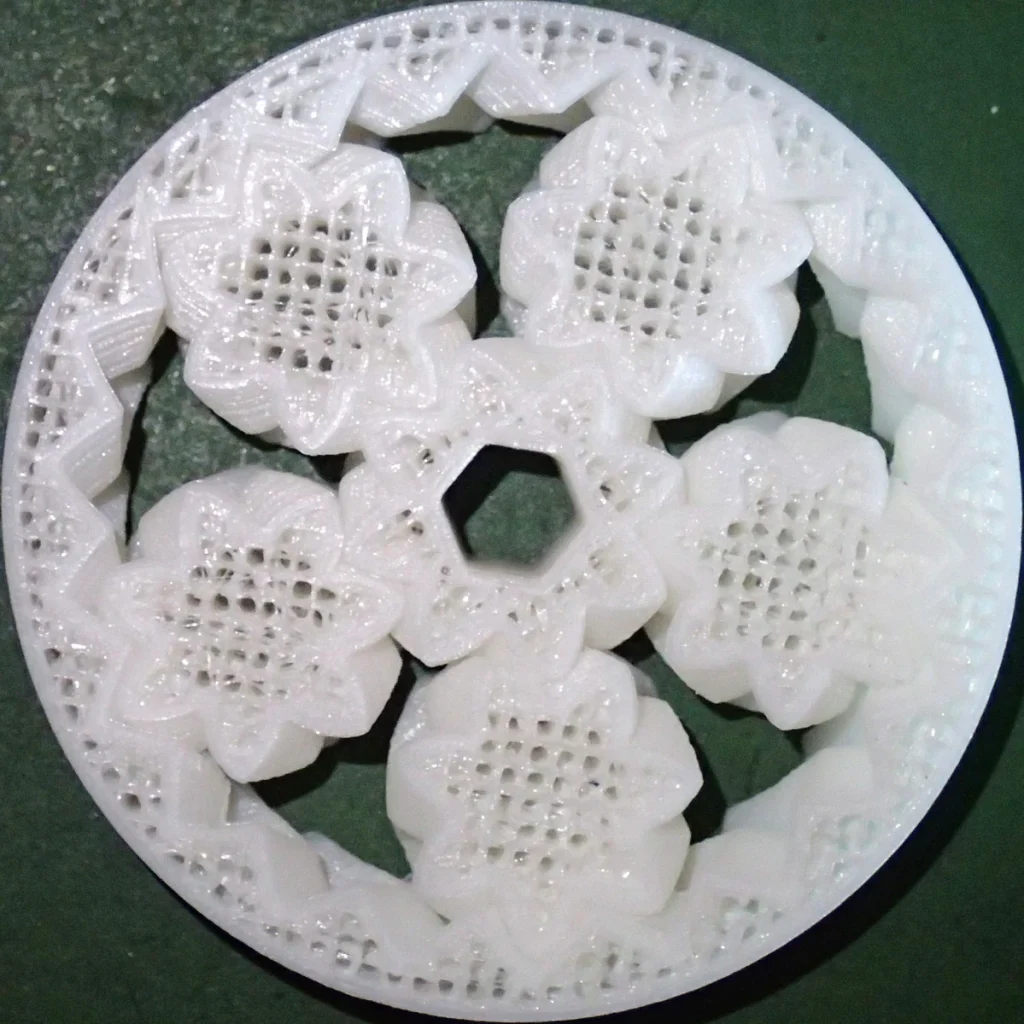 White printed planetary gear assembly with open grid infill and a central hexagonal opening on a dark surface.