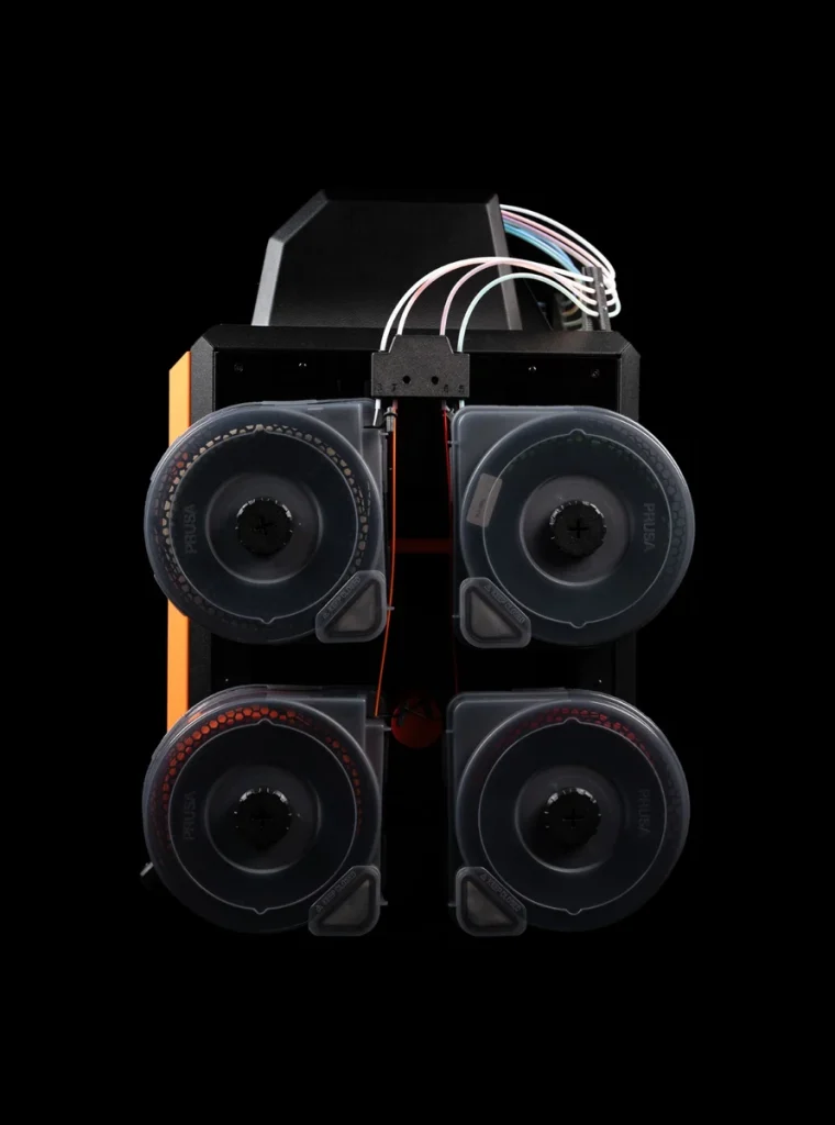 Four translucent spool dryboxes on one side of a CORE One INDX, with filament tubes curving above its top cover.