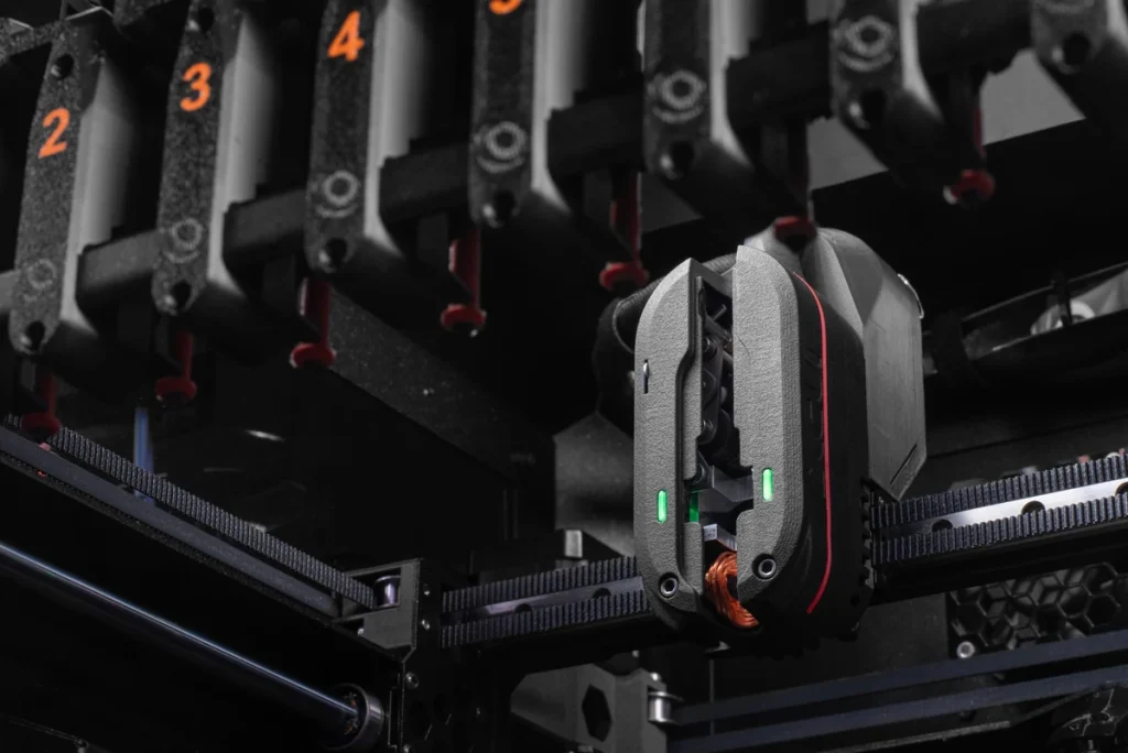 INDX head with two green lights below numbered nozzle tools, with belts crossing the foreground.