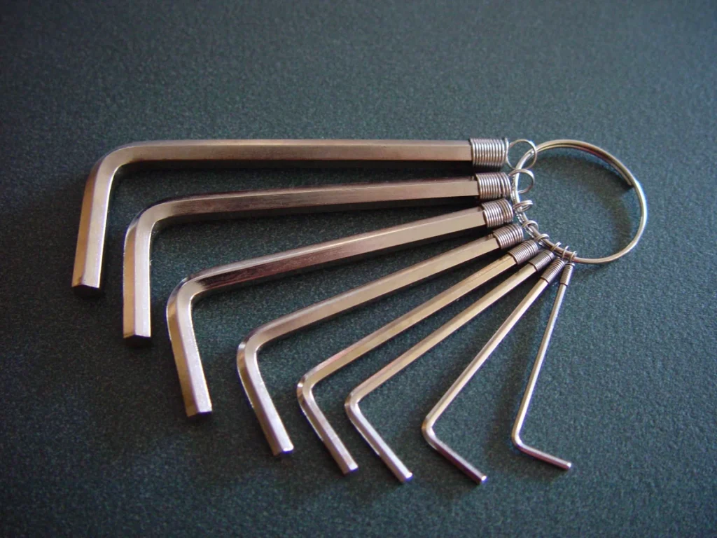 Eight L-shaped hex keys attached to a ring on a dark textured tabletop.
